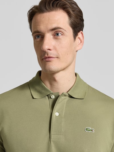 Männermodel trägt Regular Fit Poloshirt aus reiner Baumwolle von Lacoste, Optik: Unifarben, Logo-Stitching, Nahaufnahme Oberkörper.