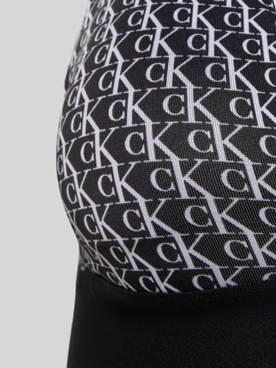 Frauenmodel trägt Slim Fit BH mit Allover-Logo-Print von Calvin Klein Underwear in Schwarz mit weißem Muster, Detailaufnahme. Elastischer Material-Mix, Hakenverschluss, verstellbare Träger.