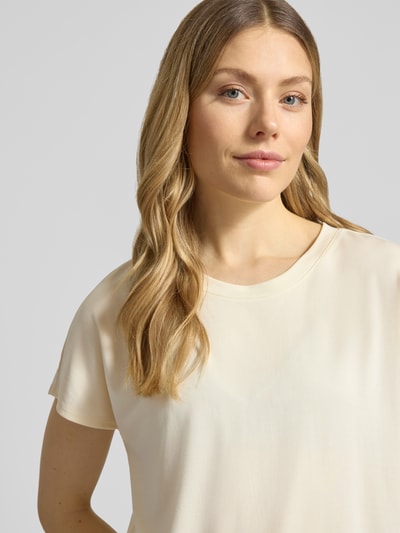 Modelka kobieca nosi damski t-shirt 'T-Shirt aus Modal-Mix mit Rundhalsausschnitt' od Jake*s Collection, mieszanka modalu, krój regular fit, okrągły dekolt, długość tyłu w rozmiarze S: 58 cm, jasny kremowy kolor, gładka faktura, zbliżenie na górną część ciała z przodu