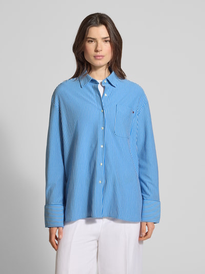 Frauenmodel trägt Oversized Langarmbluse aus Baumwoll-Mix von Tommy Hilfiger in blau-weiß gestreifter Webware, Hemdkragen, Brusttasche, Langarm, Ganzkörperansicht von vorne.