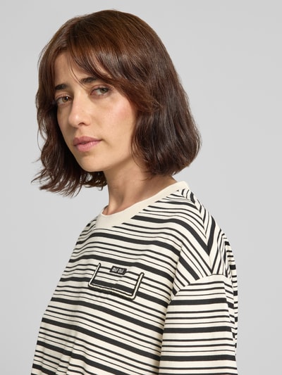 Frauenmodel trägt Boxy Fit T-Shirt mit Label-Stitching und Tunnelzug von Oui im Allover-Look, creme-schwarz, Nahaufnahme Oberkörper.