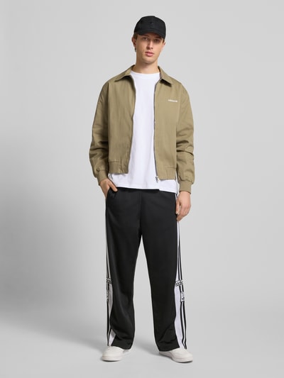 Männermodel trägt Trainingshose mit Label-Details und elastischem Bund von adidas Originals, Relaxed Fit, Modell 'ADIBREAK', Ganzkörperansicht von vorne.