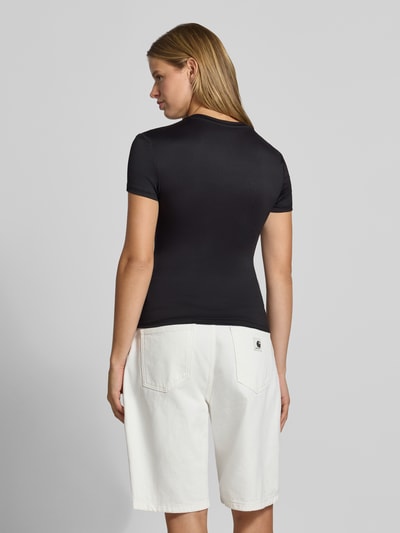 Frauenmodel trägt Slim Fit T-Shirt mit Rundhals Modell 'LULA' von PIECES in Schwarz zu weißen Shorts, Ganzkörperansicht Rückansicht.