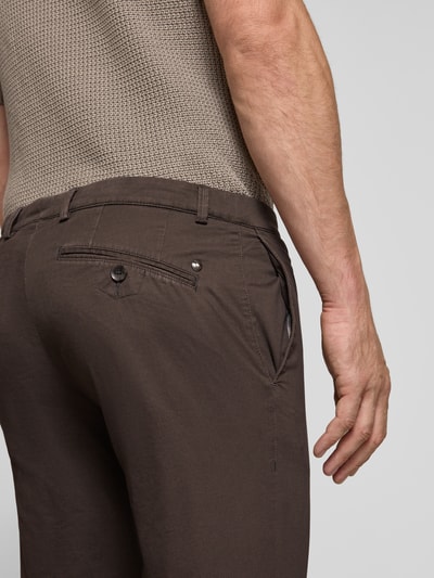 Männermodel trägt Slim Fit Chino aus Baumwoll-Mix von bugatti in Braun mit Gesäßtaschen und Münztasche, Nahaufnahme Rückansicht. Der elastische Stoff sorgt für Tragekomfort, Kontext: Herren Chino aus elastischem Baumwoll-Mix, Knopf- und Reißverschluss, Bundweite 41 cm, Innenbeinlänge 81 cm.
