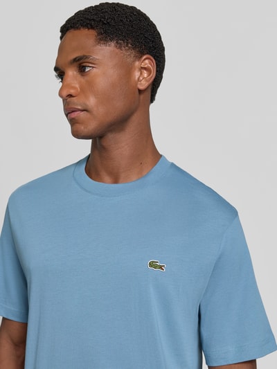 Männermodel trägt Regular Fit T-Shirt aus reiner Baumwolle von Lacoste in Hellblau mit Logo-Detail, Nahaufnahme Oberkörper. Herren T-Shirt von Lacoste