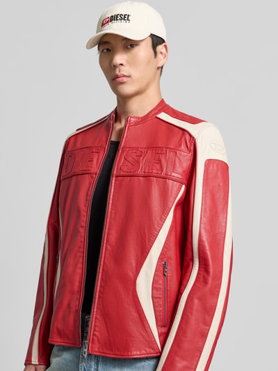 Männermodel trägt Regular Fit Jacke in Leder-Optik von Diesel in Rot mit cremefarbenen Akzenten, Reißverschlusstaschen, Nahaufnahme Oberkörper.
