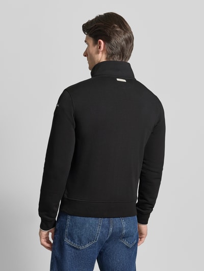 Männermodel trägt schwarze Sweatjacke mit Stehkragen Modell 'City New' von Blauer Usa aus Baumwoll-Mix, Slim-Fit, Rückenlänge 45 cm, Ärmellänge 84 cm, Label-Detail, Ganzkörperansicht Rückansicht.