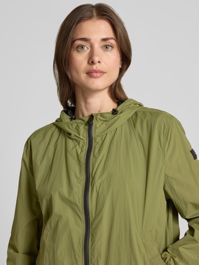Frauenmodel trägt Regular Fit Jacke mit Kapuze Modell 'Nigle' von Peuterey in Olivgrün mit Zweiwege-Reißverschluss, Nahaufnahme Oberkörper. Damen Jacke mit Eingriffstaschen, elastische Abschlüsse:, Rückenlänge 60 cm, Schulterbreite 47 cm, Brustweite 57 cm, Ärmellänge 61 cm, Größe 38.