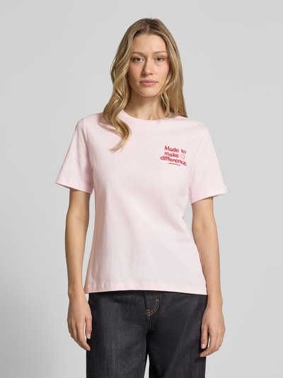 Frauenmodel trägt Regular Fit T-Shirt aus reiner Baumwolle Modell 'LUALAA EMBRO' von Armedangels, unifarben rosa, Label-Schriftzug, Feinripp, Rundhals, Kurzarm, Ganzkörperansicht von vorne.