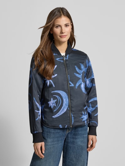 Vrouwenmodel draagt Jacke met opstaande kraag en steekzakken van Scotch & Soda, regular fit, donkerblauw met blauwe print, nahaufnahme bovenlichaam. Ruglengte maat S 57 cm, schouderbreedte 44 cm, borstwijdte 50 cm, mouwlengte 63 cm, labeldetail, ritssluiting.