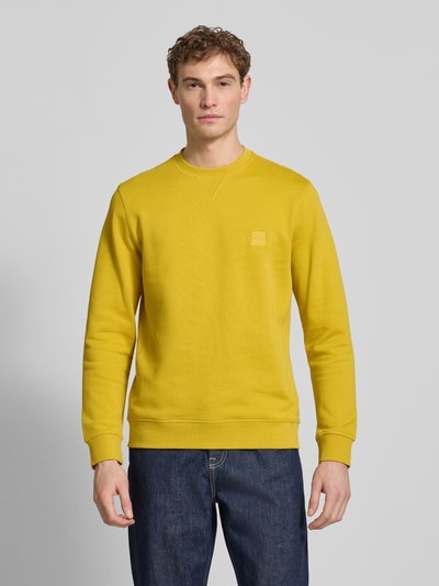 Männermodel trägt Relaxed Fit Sweatshirt aus reiner Baumwolle Modell 'WESTART' von BOSS Orange, unifarben, Rundhals, Langarm, Label Patch, Ganzkörperansicht von vorne