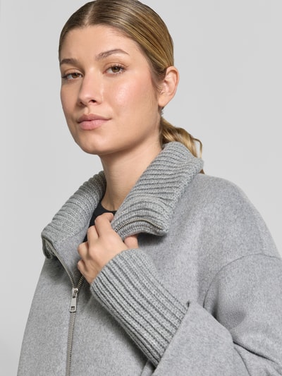 Frauenmodel trägt Mantel aus Woll-Mix mit Reißverschlusstaschen von White Label in Grau, Stehkragen, Nahaufnahme Oberkörper.