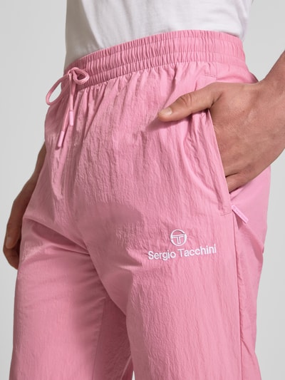 Männermodel trägt Straight Fit Stoffhose mit Logo-Stitching Modell 'Nayla' von SERGIO TACCHINI in Rosa, Nahaufnahme Oberkörper, Herren, elastischer Bund mit Tunnelzug, elastische Beinabschlüsse, Innenbeinlänge bei Größe M 77 cm.