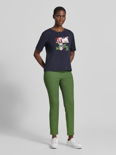 Kobiece modelka nosi Regular Fit T-Shirt aus reiner Baumwolle od Marc Cain, damski t-shirt, bawełna, kwiatowy haft, okrągły dekolt, długość tyłu w rozmiarze 36: 57 cm, widok całej sylwetki z przodu