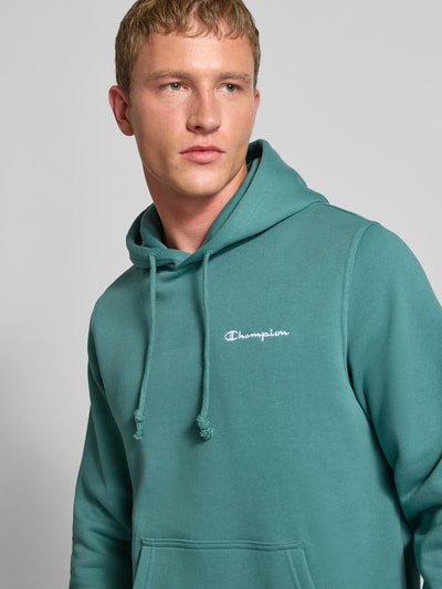 Männermodel trägt Hoodie mit Kapuze von CHAMPION aus Baumwoll-Mix, Lockerer-Schnitt, Label-Stitching, Nahaufnahme Oberkörper.