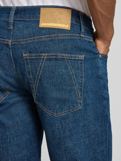 Männermodel trägt Slim Fit Jeansshorts aus Baumwoll-Mix Modell 'NAAILO' von Armedangels, Denim-Optik, Label-Patch, Nahaufnahme Rückansicht.