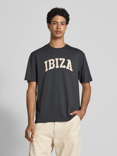 Männermodel trägt Relaxed Fit T-Shirt aus reiner Baumwolle Modell 'RICO' von Only & Sons, unifarben, Motiv-Print, Nahaufnahme Oberkörper.