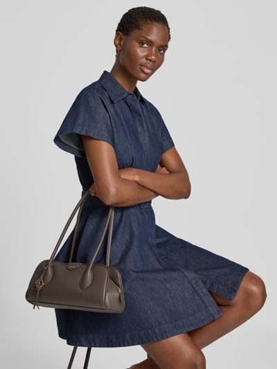 Kobiece model prezentuje Henkeltasche mit Label-Detail od CK Calvin Klein, brązowa, gładka faktura, widok całej sylwetki z przodu.