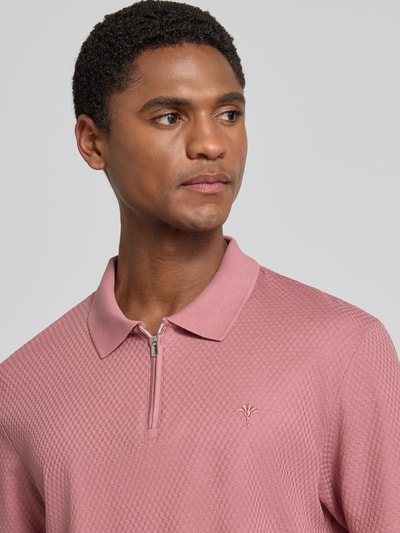 Männermodel trägt Regular Fit Poloshirt mit Strukturmuster Modell 'Tibaris' von JOOP! COLLECTION in Rosa, Nahaufnahme Oberkörper, Label-Stitching, Polokragen, Reißverschluss, Rückenlänge 70 cm bei Größe M.
