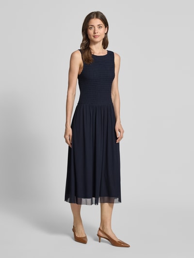 Frauenmodel trägt Midikleid aus Mesh mit Smok-Details von Christian Berg Woman Selection in Dunkelblau, Gerader-Schnitt, Rundhalsausschnitt, Ganzkörperansicht von vorne. Rückenlänge bei Größe 36: 120 cm, Brustweite: 35 cm.