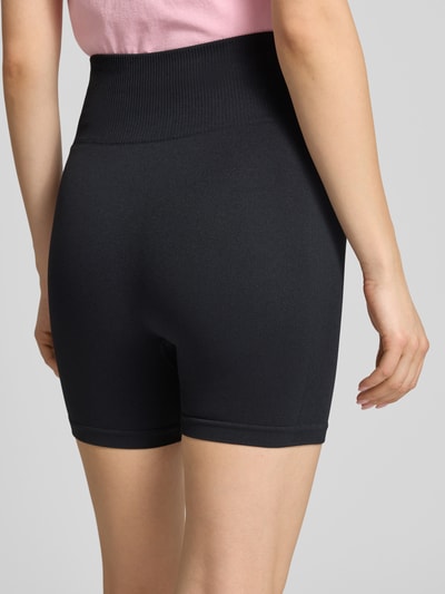 Frauenmodel trägt Slim Fit Shorts mit Logo-Print Modell 'Restore' von P.E Nation aus elastischem Material-Mix, schwarzer Farbton, breiter Bund, Ganzkörperansicht Rückansicht.