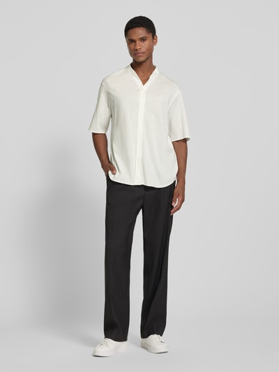 Männermodel trägt Regular Fit Freizeithemd mit V-Ausschnitt und Label-Stitching von Emporio Armani in Reine Baumwolle, Ganzkörperansicht von vorne. Rückenlänge 74 cm, Schulterbreite 52 cm, Ärmellänge 27 cm, Farbe creme mit glatter Textur.