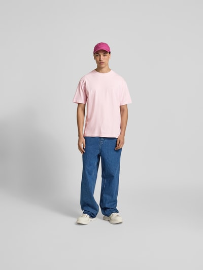 Männermodel trägt Regular Fit T-Shirt aus reiner Baumwolle von Closed in Rosa, Rundhalsausschnitt, Used-Look, Label-Print, Ganzkörperansicht von vorne.