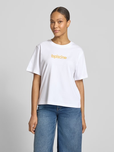 Kobiece modelka nosi Regular Fit T-Shirt aus reiner Baumwolle Modell 'MACY' von Selected Femme, biała bawełna, nadruk z przodu, krój regular fit, krótki rękaw, dekolt okrągły, widok całej sylwetki z przodu.
