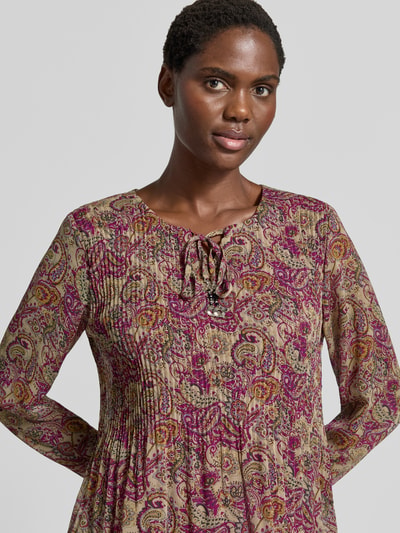Frauenmodel trägt Relaxed Fit Bluse mit Allover-Paisley-Print Modell 'Leonora' von ZABAIONE, Zierschleife, Nahaufnahme Oberkörper.