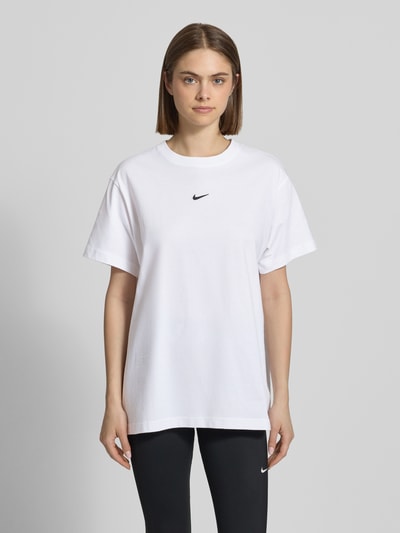 Frauenmodel trägt T-Shirt mit Logo und Rundhalsausschnitt von Nike in Weiß, Reine Baumwolle, Relaxed-Fit, Rückenlänge 69 cm, Ganzkörperansicht von vorne.