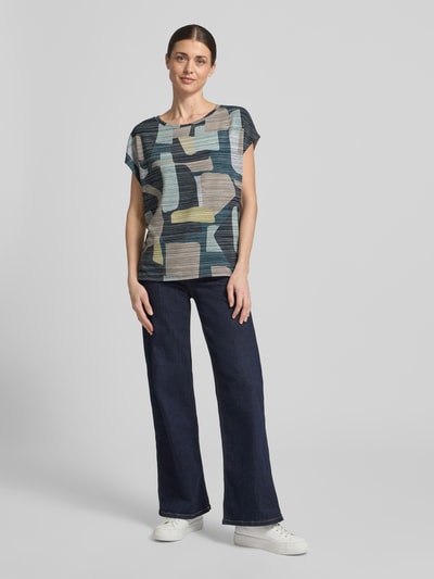 Vrouwenmodel draagt 'Oversized Bluse aus Viskose-Mix' van Tom Tailor, meerkleurig camouflage allover, crew neck, zonder mouwen, stretch viscose-mix, oversized fit, zijslitten, vooraanzicht hele lichaam