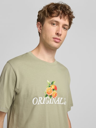 Mężczyznamodel nosi Regular Fit T-Shirt mit Statement-Print Modell 'Eres' od Jack & Jones, bawełna, krój regular fit, dekolt okrągły, przód z napisem i nadrukiem owoców, kontekst: długość tyłu w rozmiarze M: 61 cm, ujęcie: zbliżenie górnej części ciała z przodu