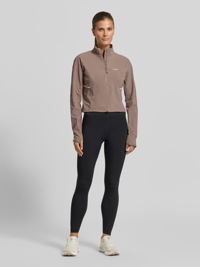 Frauenmodel trägt Cropped Pullover für intensive Anstrengungen und Beschleunigung von Salomon aus Material-Mix mit Stretch-Anteil, Logo, Stehkragen und Reißverschluss, Rückenlänge bei Größe S: 47 cm, Ganzkörperansicht von vorne.