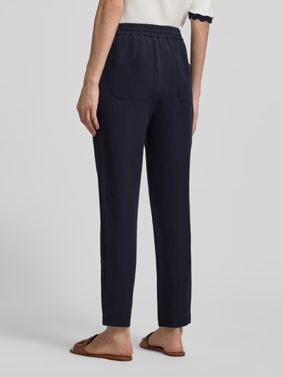 Kobiece modelka nosi Straight Fit Stoffhose aus Viskose-Mix mit Leinen-Anteil von Marc Cain, granat, materiał stylizowany na len, wpuszczane kieszenie, elastyczny pas z tunelem, szerokość w rozmiarze 36: 37 cm, długość wewnętrzna nogawki 66 cm, Ganzkörperansicht Rückansicht.