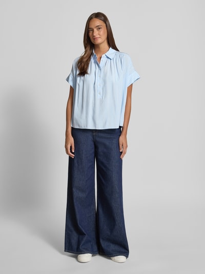 Frauenmodel trägt Relaxed Fit Bluse aus Viskose Modell 'Zafine' von Someday mit Hemdblusenkragen und Knopfleiste in Hellblau, Ganzkörperansicht von vorne. Rückenlänge bei Größe 36: 63 cm