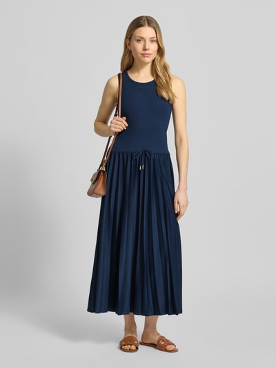 Vrouwenmodel draagt Regular fit Maxikleid met logo-patch model 'Tildy' van JOOP!, donkerblauw, taille met tunnelkoord, plissé-effect, mouwloos, elastische katoenmix, midi-lengte, getailleerde pasvorm, frontale totaalaanzicht.