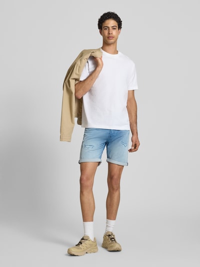 Männermodel trägt Jeansshorts im Destroyed-Look Modell 'RICK' von Jack & Jones aus Baumwoll-Viskose-Mix, Regular-Fit, hellblau. Ganzkörperansicht von vorne.