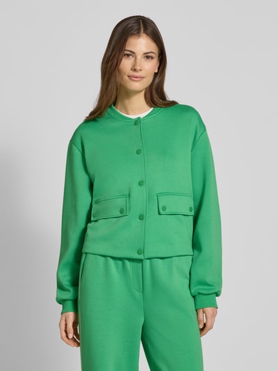 Frauenmodel trägt Regular Fit Jacke mit Viskose-Anteil Modell 'Kate' von ICHI in kräftigem Grün mit Stehkragen, Pattentaschen und Knopfleiste, elastischer Material-Mix, elastische Ärmelabschlüsse, glatte Textur, Ganzkörperansicht von vorne.