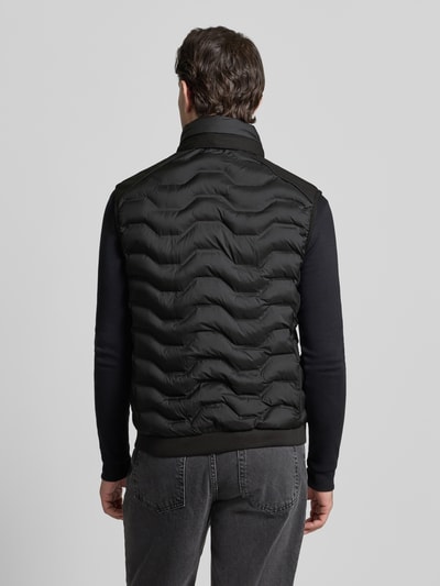 Männermodel trägt Regular Fit Steppweste mit Kapuze im Kragen von Tom Tailor, unifarben, Stehkragen, Reißverschlusstaschen, Ganzkörperansicht Rückansicht