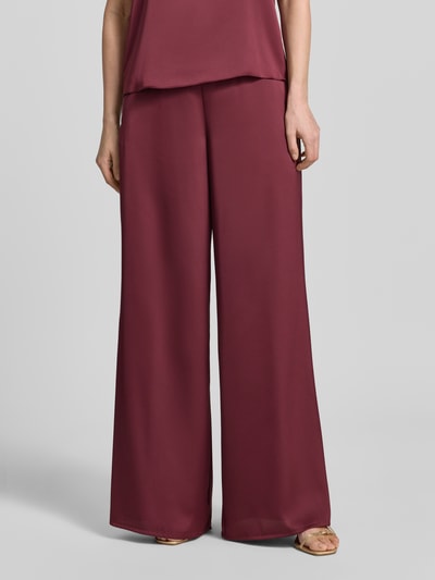 Frauenmodel trägt Wide Leg Hose aus Satin mit elastischem Bund von V by Vera Mont in Bordeauxrot mit Eingrifftaschen, Nahaufnahme Oberschenkel bis Fuß.