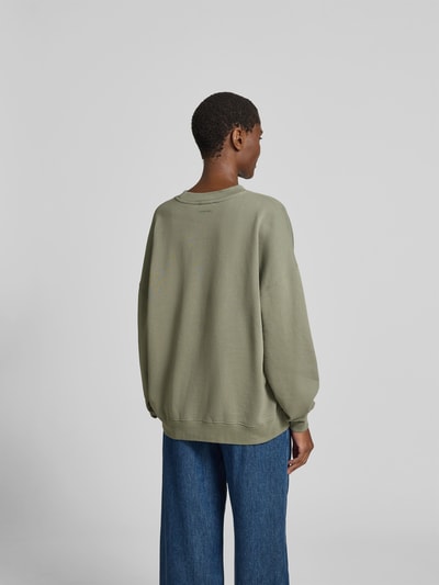 Frauenmodel trägt Relaxed Fit T-Shirt mit Logo-Print von Anine Bing aus reiner Baumwolle, olivegrün, Rundhalsausschnitt, eingefasste Ärmelabschlüsse, Rückenlänge bei Größe S 60 cm, Ganzkörperansicht Rückansicht.
