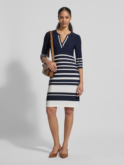 Modelka prezentuje knielanges Kleid mit V-Ausschnitt von Christian Berg Woman Selection, mieszanka materiałów z dodatkiem streczu, taliowany krój, długość do kolan, dekolt w serek, rękaw o dł. 3/4, długość tyłu w rozmiarze 36: 92 cm, szerokość w rozmiarze 36: 44 cm, długość rękawów w rozmiarze 36: 43 cm, granatowe i białe pasy, gładka tekstura, całkowity widok z przodu