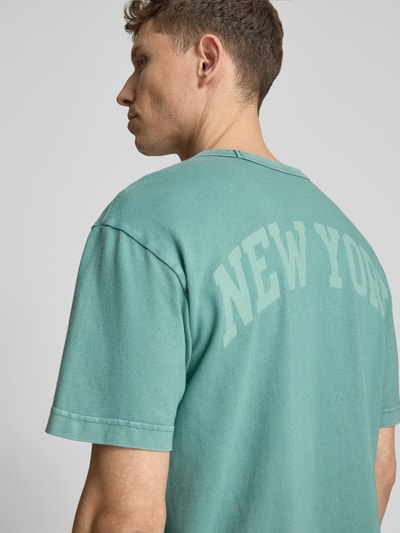 Männermodel trägt T-Shirt mit Logo und Rundhalsausschnitt von GAP, Reine Baumwolle, Regular-Fit, Rückenlänge 61 cm, Nahaufnahme Rückansicht.