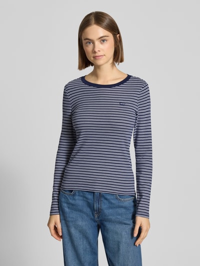 Modelka nosi Slim Fit Longsleeve mit Logo-Stitching Modell 'Essential' od Levi's®, bawełna, granatowe paski, okrągły dekolt, widok całej sylwetki z przodu.