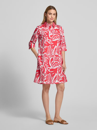 Frauenmodel trägt Knielanges Hemdblusenkleid mit verdeckter Knopfleiste von Christian Berg Woman aus Reine Baumwolle, Straight Fit, 1/2-Arm, rotes und weißes Muster, Hemdblusenkragen, Knielänge, glatte Struktur, Ganzkörperansicht von vorne.