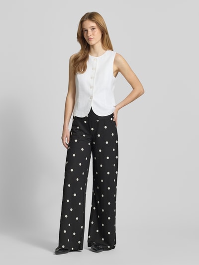 Vrouwenmodel draagt Wide Leg Pants aus Viskose-Mix met seitlichem Reißverschluss van Gina Tricot, zwart met witte polkadots, los model, bandwijdte maat S 41 cm, binnenbeenlengte maat S 82 cm, polkadotpatroon, ganzkörperansicht van voren.