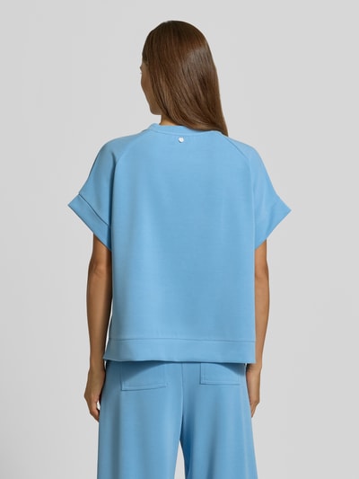 Frauenmodel trägt T-Shirt mit elastischen Abschlüssen von Rich & Royal in Hellblau, entspannter Schnitt, detailarme Textur, Ganzkörperansicht Rückansicht. Modal-Mix mit Stretch-Anteil, Rundhalsausschnitt, Relaxed Fit.