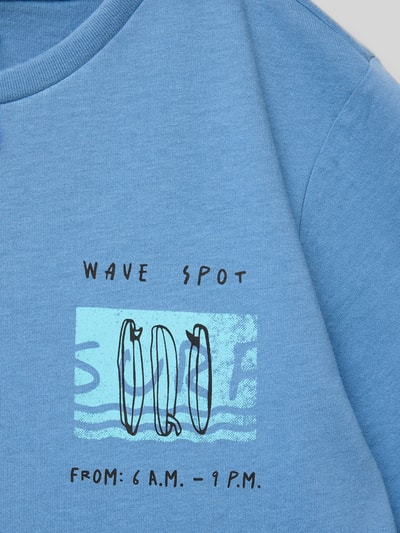 Mädchen trägt Regular Fit T-Shirt aus reiner Baumwolle von s.Oliver RED LABEL in Blau, Optik: Unifarben, Motiv-Print, Jersey-Textur, Nahaufnahme Oberkörper.