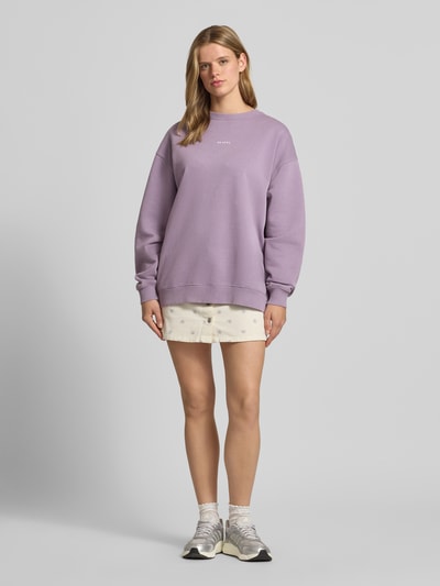 Frauenmodel trägt Oversized Sweatshirt mit Rundhalsausschnitt und Logo von OH APRIL, Flieder, Baumwoll-Mix, Ganzkörperansicht von vorne.