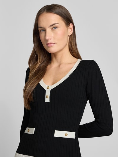Frauenmodel trägt Slim Fit Longsleeve aus Viskose-Mix Modell 'Laurel' von Guess in Strick-Optik mit Zierknöpfen, Nahaufnahme Oberkörper.